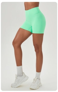 Detail of mint green high-waisted yoga shorts showing wide waistband on a model