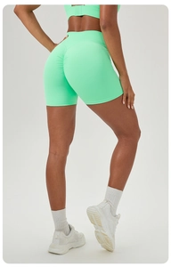Detail of mint green high-waisted seamless scrunch butt lifting yoga shorts on model