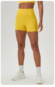Detail of high-waisted yellow yoga shorts featuring seamless stretch fabric for fitness