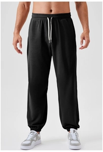 Detail of men's black joggers showing elastic waistband with white drawstrings