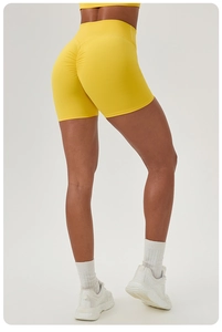 Detail of high waisted yellow yoga shorts featuring ruched peach butt lifting effect