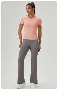 Détail du t-shirt de sport rose ajusté avec coutures et pantalon de yoga évasé gris