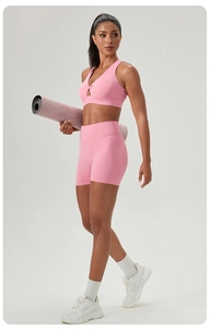 Detailed side view of pink high-waist yoga shorts and matching knot sports bra