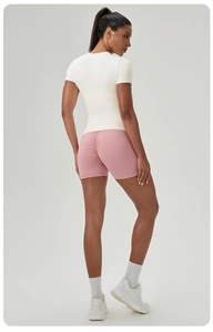 Détail du short de sport rose froncé et du haut de yoga crème ajusté sur un mannequin