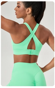 Close-up of mint green sports bra featuring X-shaped cross straps and buckle closure detail