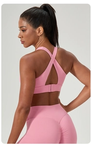 Close-up of pink sports bra showing crisscross straps and three-row buckle closure