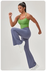 Canotta sportiva a coste verde erba e pantaloni yoga a zampa viola su modella fitness