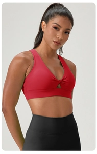 Detail of red yoga bra featuring front twist knot and teardrop cutout for fitness