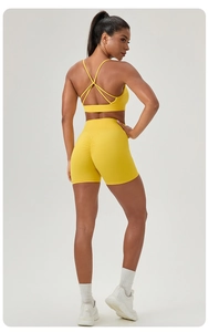 Vue détaillée du soutien-gorge de sport jaune croisé au dos et du short de fitness sculptant