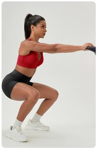 Side view detail of high-support red sports bra and high-waist seamless black shorts