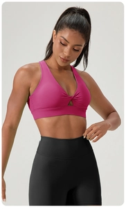 Detail view of rose red sports bra with front twist knot and triangular cutout feature