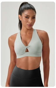 Detail of sage green yoga bra featuring front twist knot and teardrop cutout detail