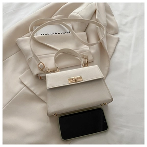 Detail view of cream vintage handbag with gold turn-lock and rounded handle on blazer