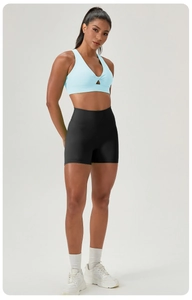 Detail of light blue sports bra with V-neck knot design and black high-waist yoga shorts