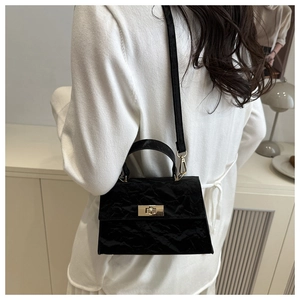 Detail of black textured handbag with golden twist lock and elegant top handle strap