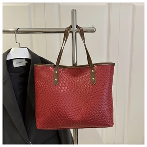 Detail of red woven tote bag showing double-sided grid texture and golden rivets