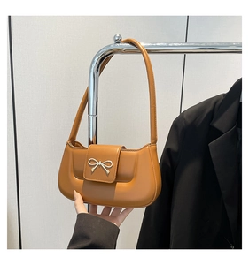 Detail of a vintage ginger leather baguette bag featuring a silver bow metal accessory