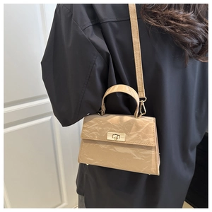 Detail of beige wrinkled texture crossbody bag with gold lock and sleek top handle