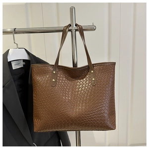 Detailed view of brown woven tote bag with large capacity and golden rivet hardware