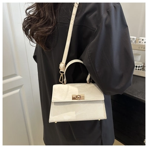 Close-up of a white marble texture handbag with a golden clasp on a person's shoulder