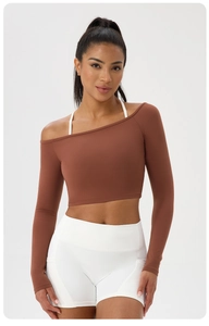 Détail d'un crop top asymétrique marron avec épaule dénudée et fine bretelle blanche