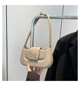 Detail of apricot shoulder bag featuring a metallic bow buckle and leather texture