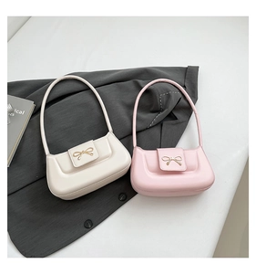 Close-up of minimalist leather shoulder bags featuring elegant gold bow metal accents
