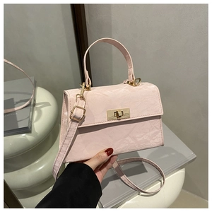 Detail view of pink suede crossbody bag featuring gold metal twist lock and textured finish