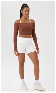 Détail du haut court à épaules dénudées rouge brun et short de yoga blanc taille haute