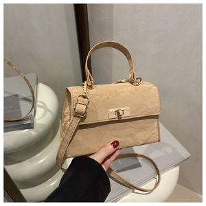 Close-up of pleated texture handbag with golden clasp being held in a stylish setting