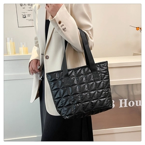 Close-up of a stylish black quilted tote bag featuring elegant diamond stitching and gloss finish