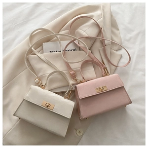 Detail view of mini crossbody bags with gold metal clasps on a beige blazer background
