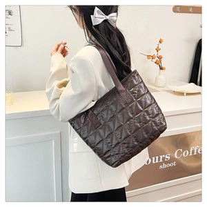 Detail view of large dark brown quilted tote bag with glossy finish and nylon strap