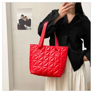 Detailed view of red quilted nylon tote bag with large triangle stitching pattern