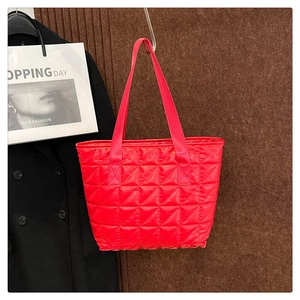 Detail of red quilted nylon tote bag with rhombus stitching and durable woven handles