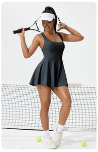 Detail of dark grey tennis dress featuring racerback design and pleated skirt on court