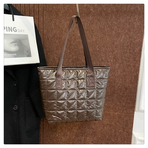 Detailed view of dark brown quilted tote bag with glossy finish and wide straps