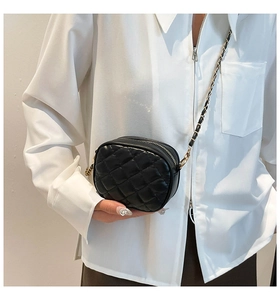 Détail d'un mini sac bandoulière noir matelassé porté par un mannequin en chemise blanche