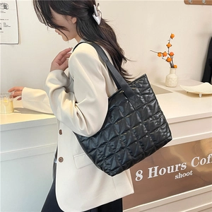 Quilted rhombus tote bag in black high-gloss fabric carried by a model in a cafe