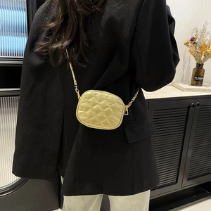 Sac à bandoulière matelassé jaune avec chaîne dorée porté par un mannequin
