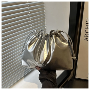 Detail of silver metallic drawstring bucket bag featuring pleated texture and soft shape