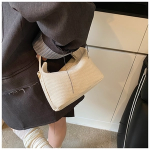 Détail d'un sac à main tissé beige avec anneau en métal doré et texture raffinée