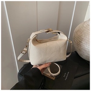 Détail du sac à main tissé beige avec fermoir doré et bandoulière élégante