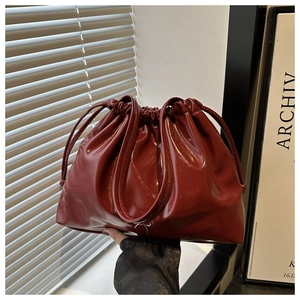 Detail of burgundy glossy bucket bag with drawstring texture and thin shoulder strap