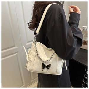 Detail of cream white shoulder bag with black metal butterfly and silver chain strap