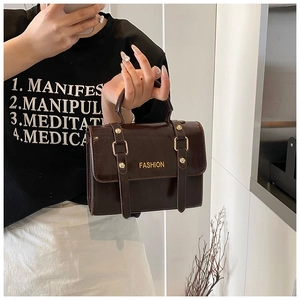 Detail of dark brown patent leather handbag with glossy finish and gold FASHION lettering