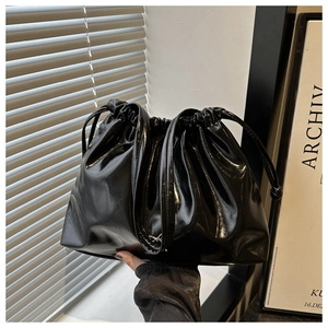 Close-up of a black glossy drawstring tote bag with elegant pleated cloud texture