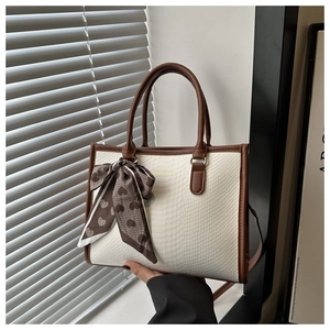 Close-up of white snake pattern tote bag with brown trim and heart print scarf detail