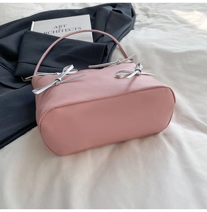 Pink leather shoulder bag detail with elegant silver bow ties and slim top handles