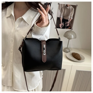 Détail du sac seau noir avec lanières en cuir marron et fermoir rotatif argenté élégant
